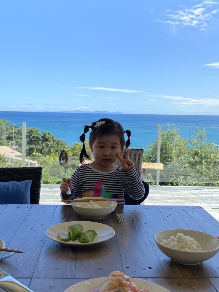 A child having breakfast on a terrace overlooking the sea
