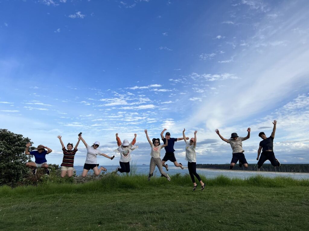 Travellers jumping together on a hill overlooking the sea