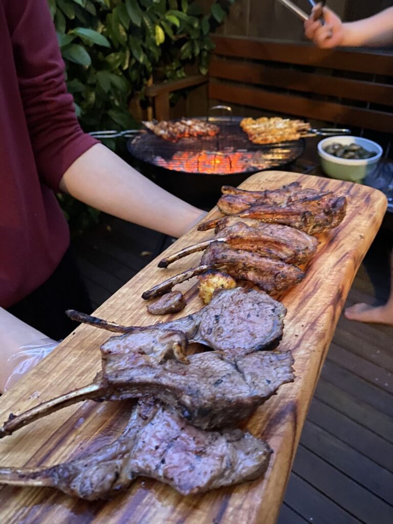Grilled lamb chops and a barbecue grill on a wooden board